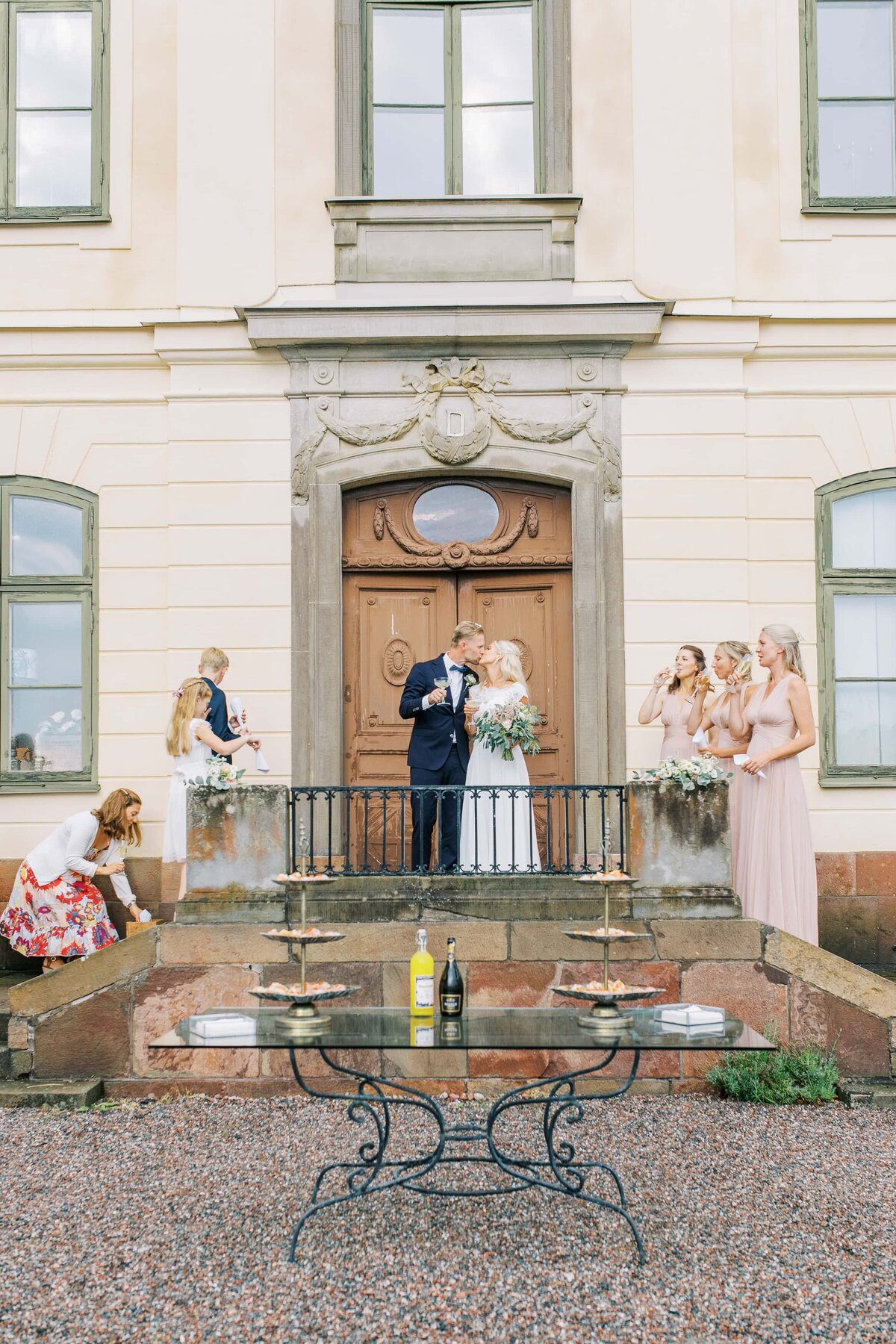 brudpar kysser varandra på trappen när de gratuleras av bröllopsgäster