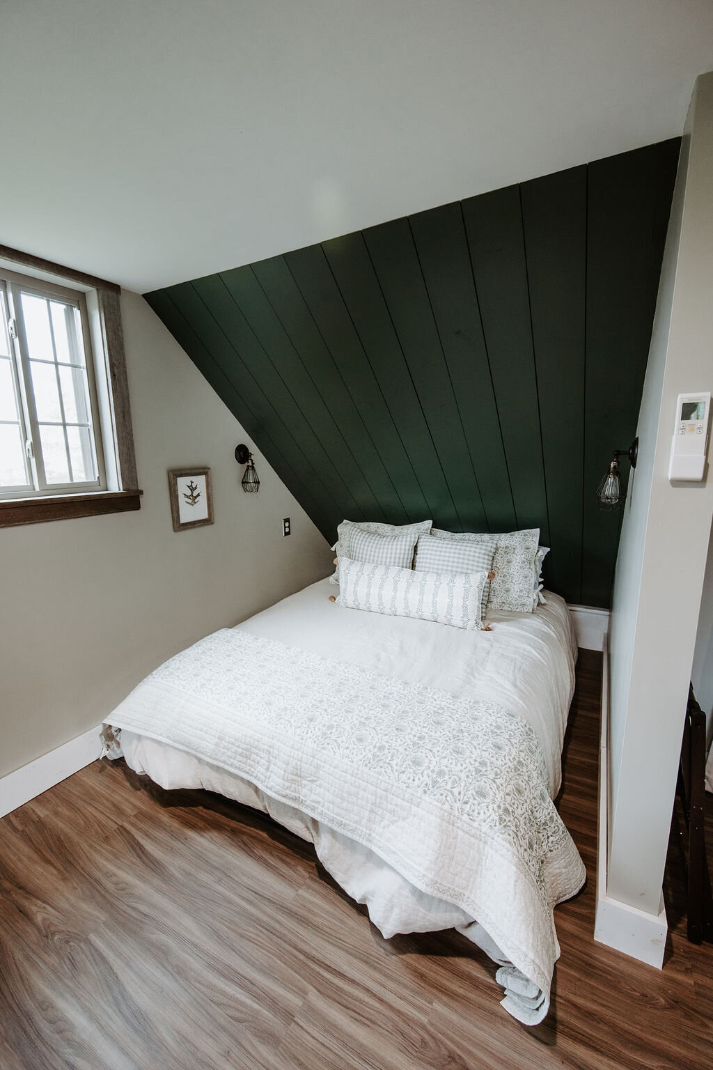 a view of the queen size bed with studio mcgee bed linens quilt and pillows in sage green against an olive green shiplap wall at Willowbrook wedding venue in PIttsburgh