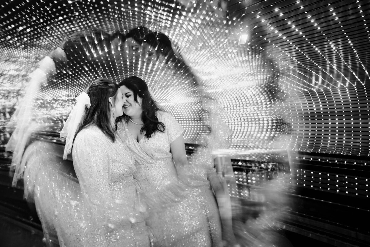 Two brides kissing with a spiral light effect around them.