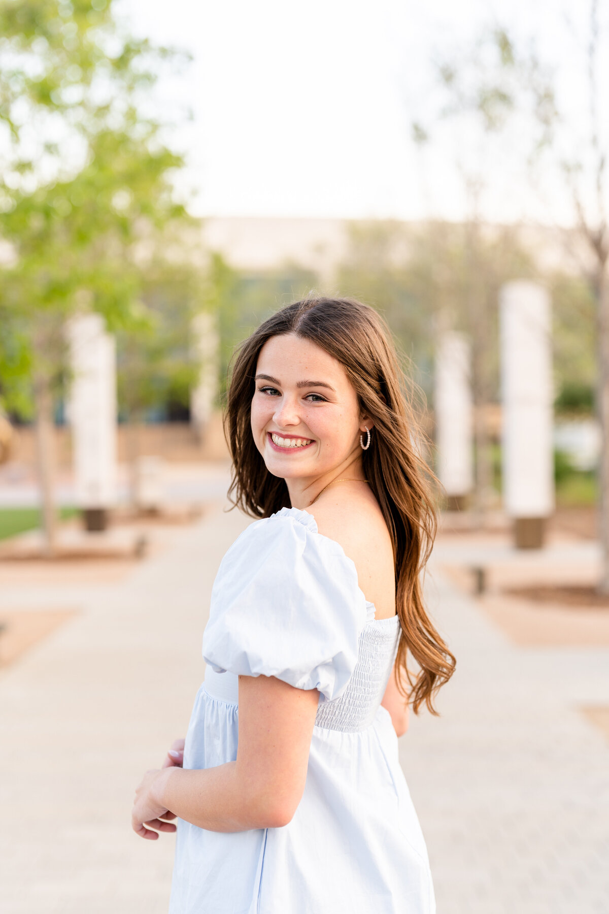 Texas A&M senior girl looking over shoulder while wearing blue dress in Aggie Park