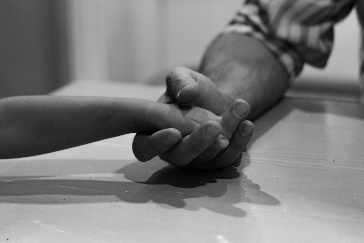 dad holding hands with toddler son to pray at dinner