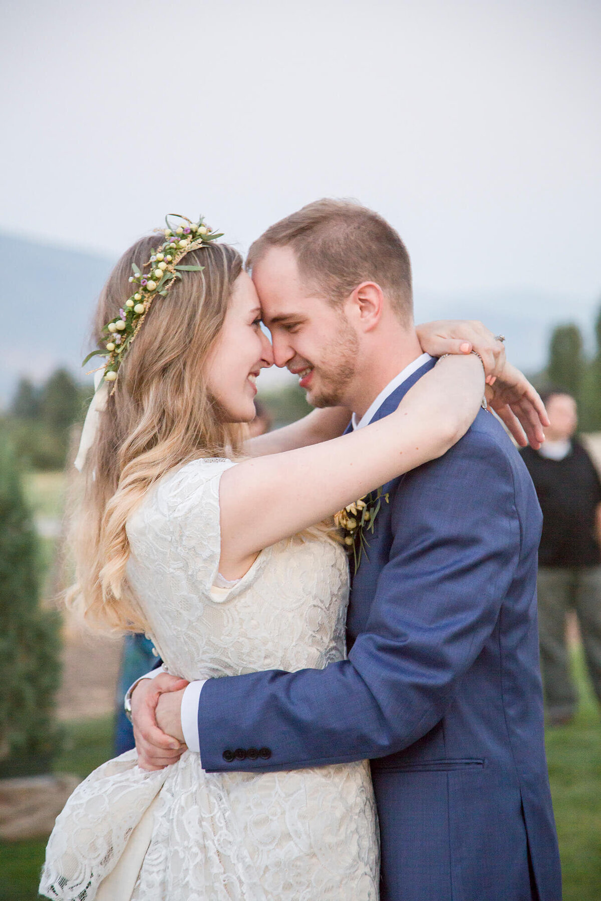 blonde bride and groom in blue suit holding each other close during their first dance at lovely sunset reception