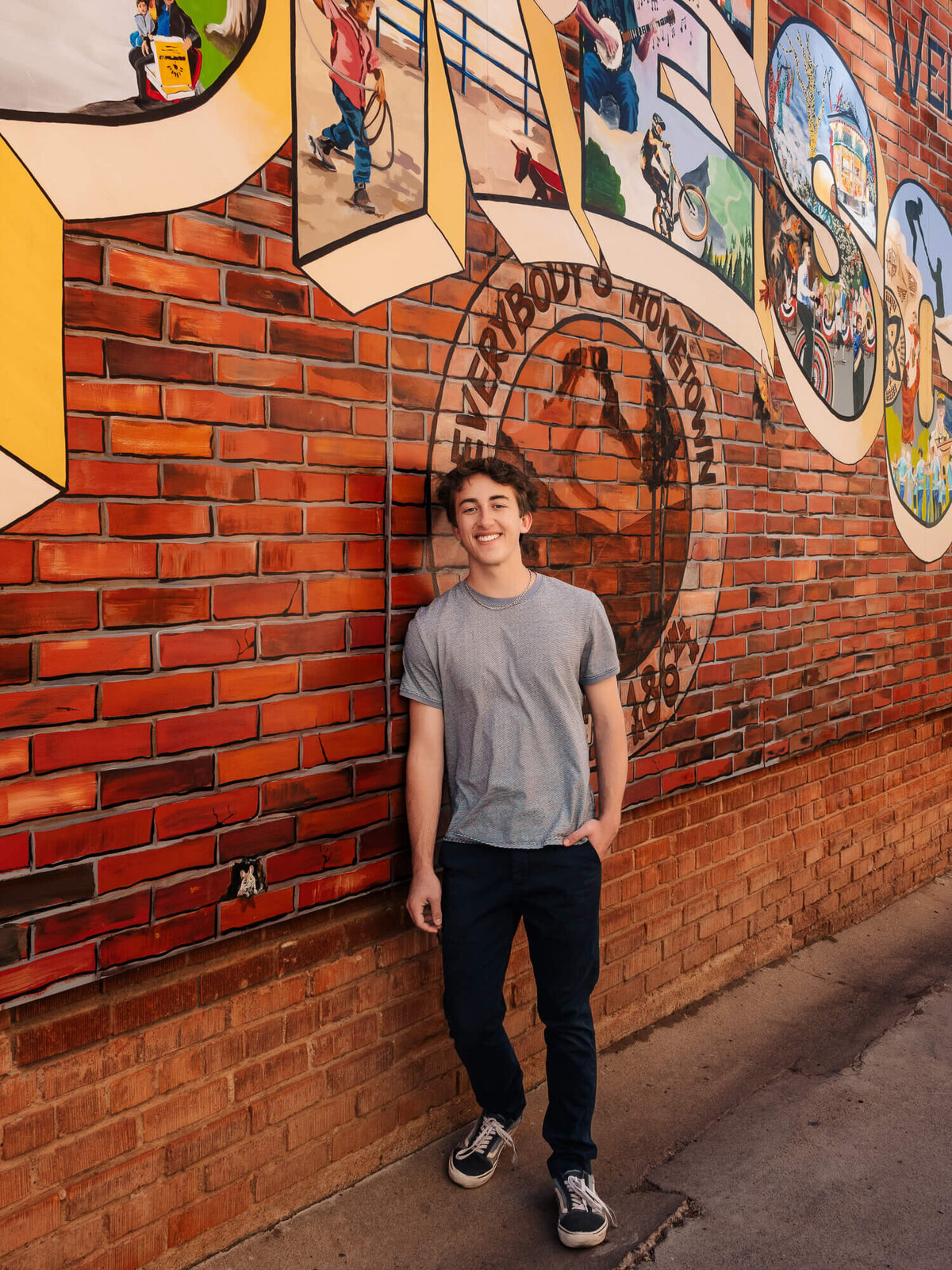Young man poses in front of mural behind Whiskey Row in session with Prescott senior photographer Melissa Byrne