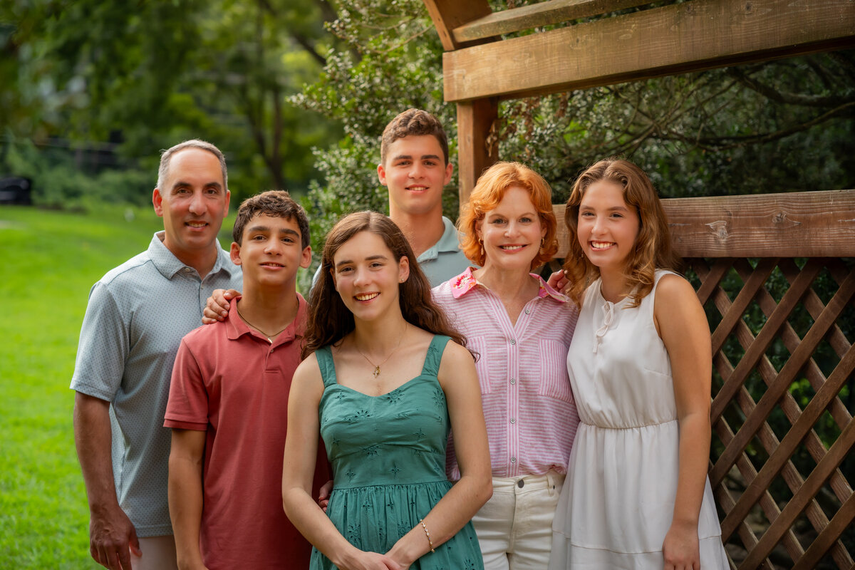 family of six posing in front of a lattice fence, captured by Capture Joy Photography, Northern Virginia family photographer.
