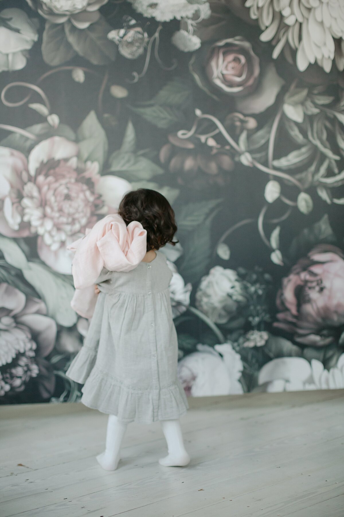 Toddler holds a blanket in front of a photography studio backdrop.
