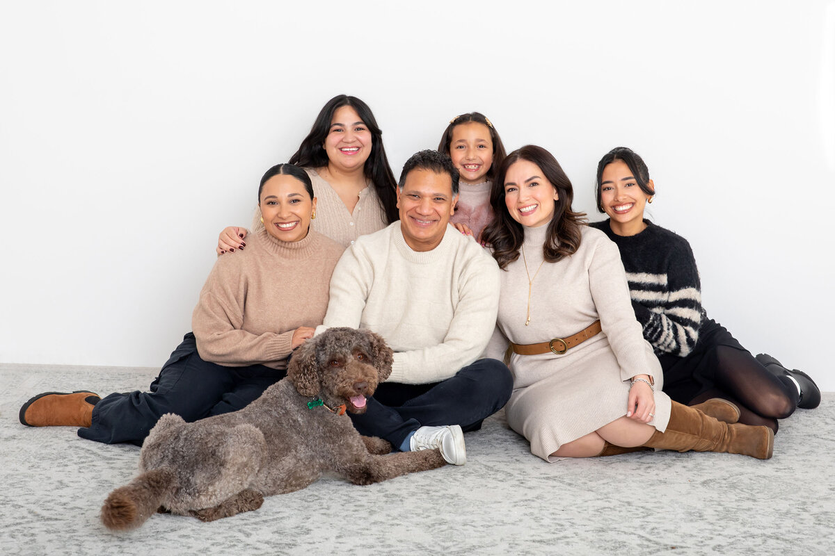 A joyful family of six—parents and four children—dressed in a beautifully coordinated color palette, sharing smiles and close connections during their family photo session, capturing the warmth and togetherness of the moment