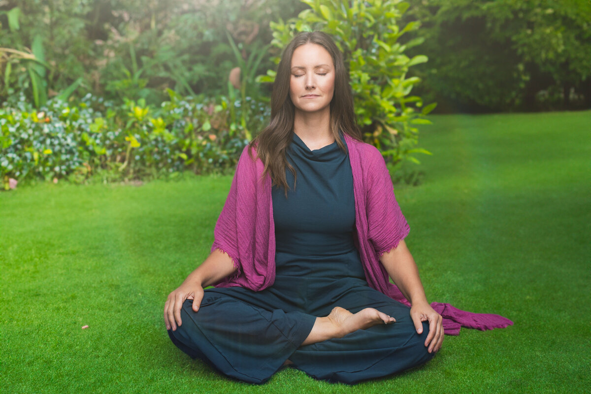 Discover the serene portrait of a woman practicing yoga outdoors, set in a lush green garden. She wears a navy outfit complemented by a vibrant purple shawl, exuding tranquility and mindfulness. Ideal for personal branding and professional headshots in Cincinnati, this image highlights the expertise of our Cincinnati-based portrait photography studio.