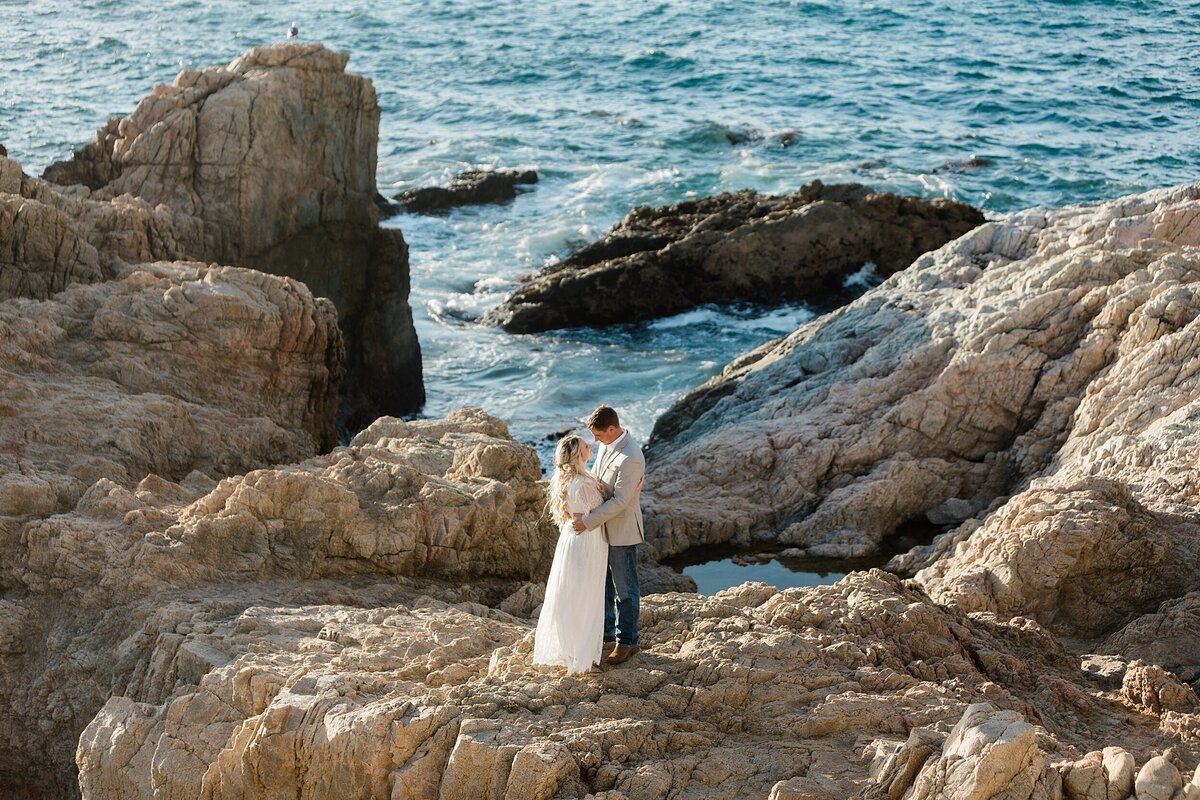 The bride and groom stand on the cliff edges for their Big Sur elopement