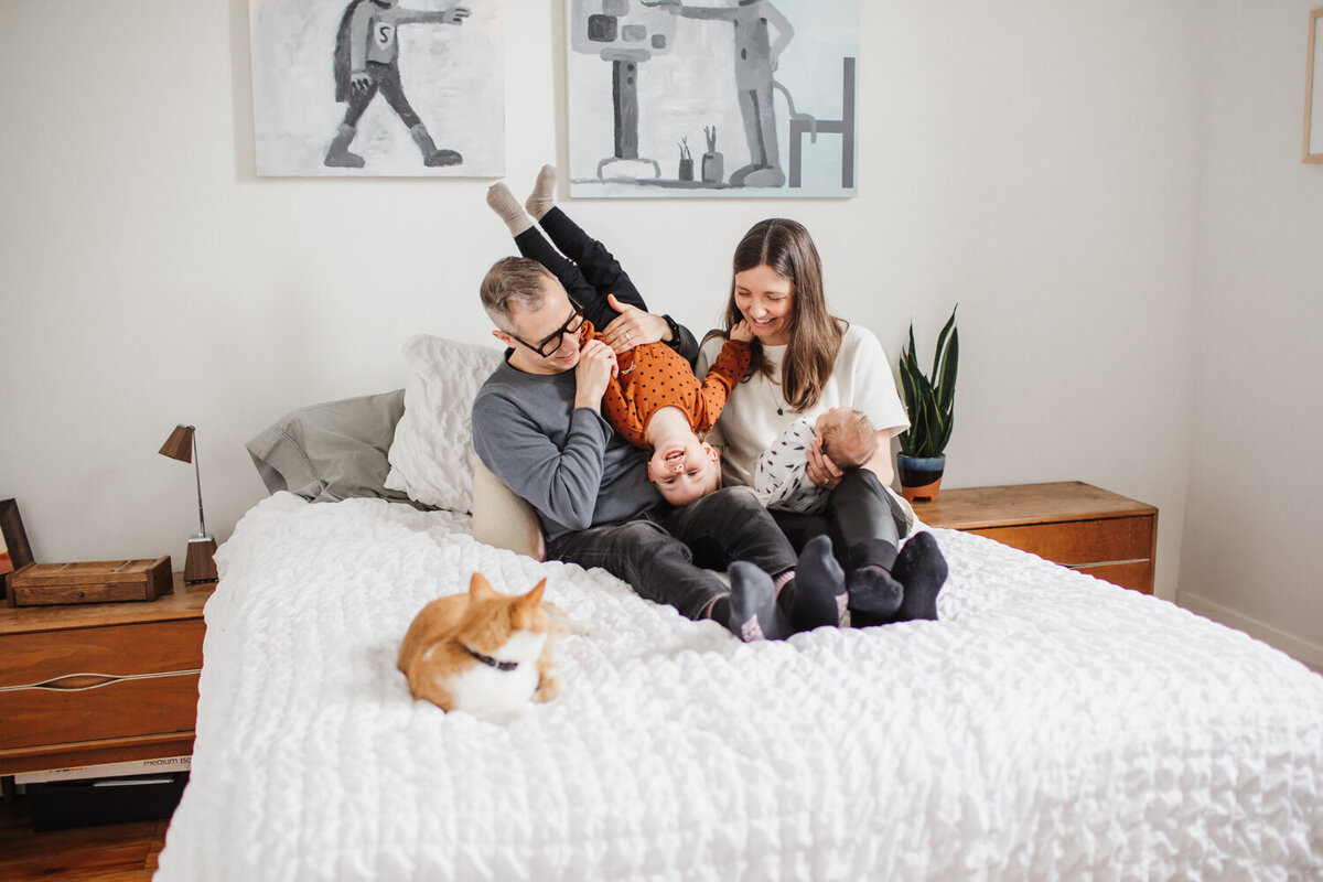 Family portrait with cat on bed during Toronto Newborn Photography session