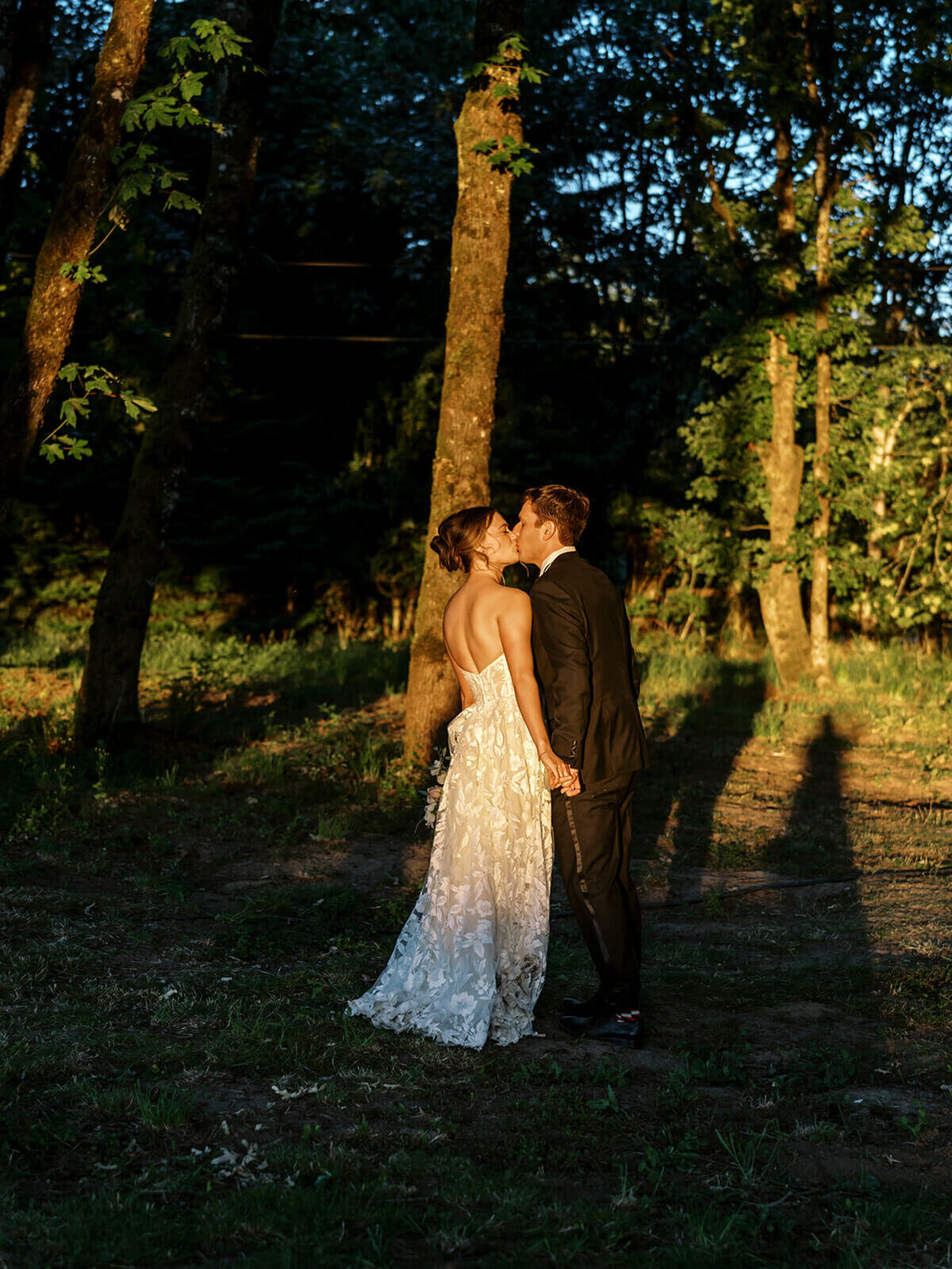 A bride and groom kiss under trees in Albany, Oregon.