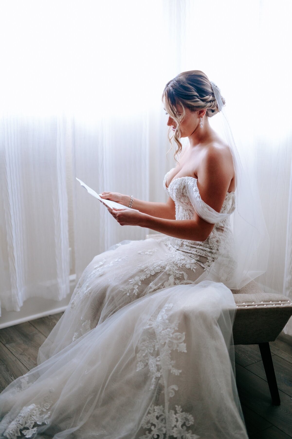 Bride reading a note from her husband in her suite before walking down the aisle.
