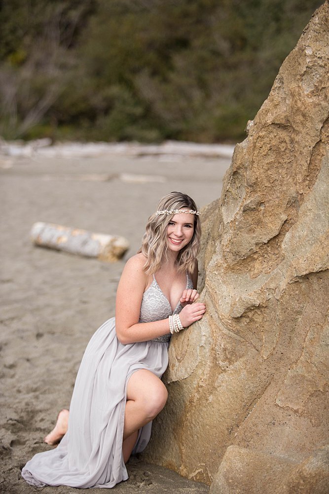 girl in flowy gown near rock on the beach