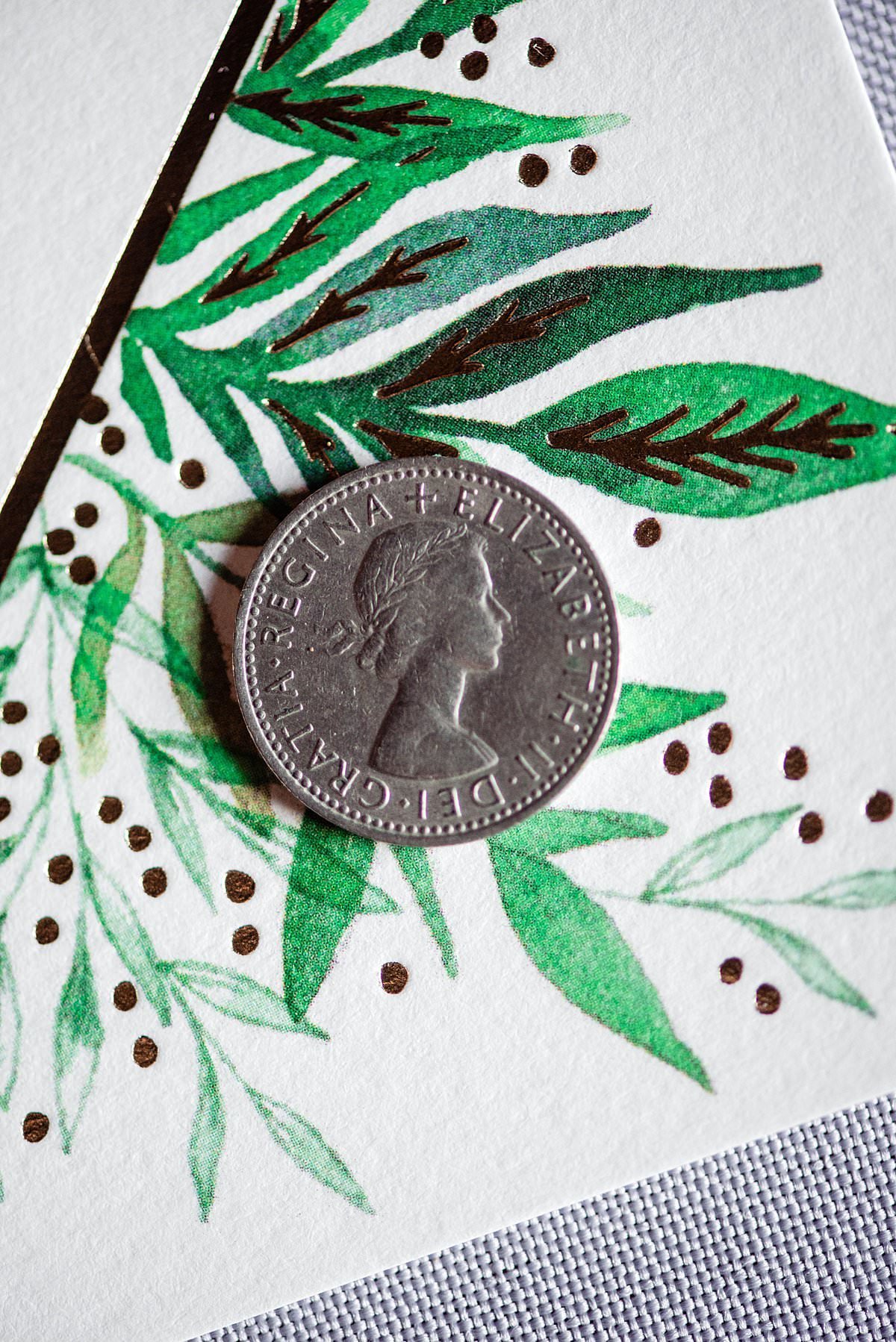 Silver sixpence on top if a greenery stationary design