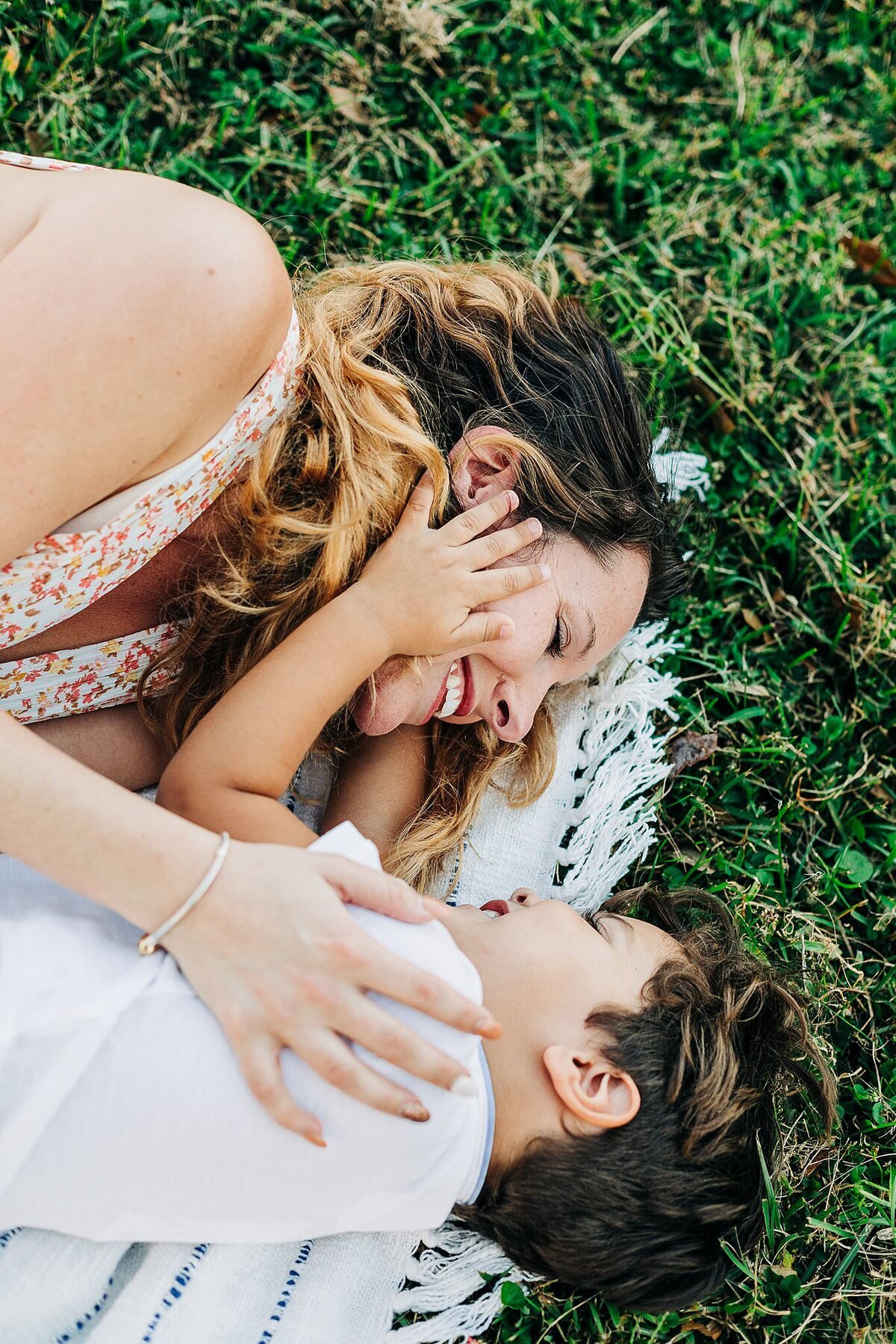 Mom and son on the grass holding each other's faces and laughing