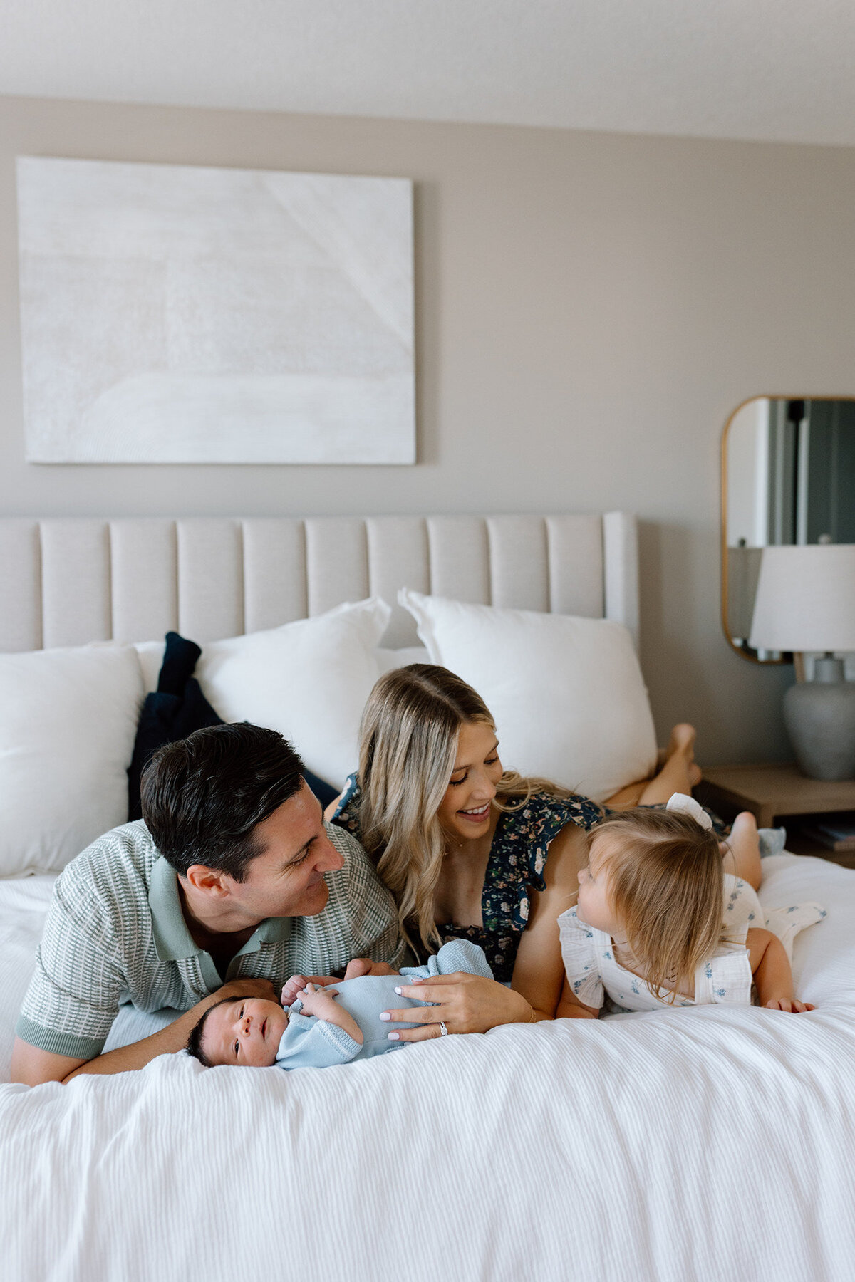 Parents sitting on bed with baby during calm, intentional newborn session