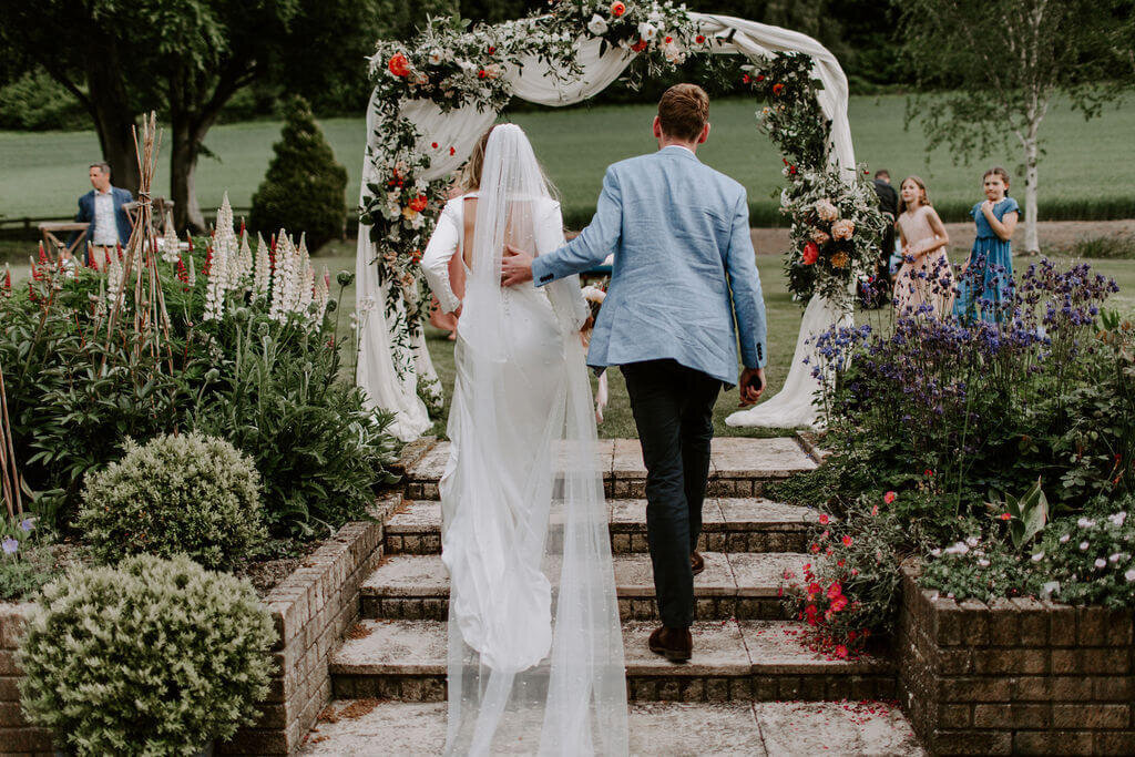 BRIDE AND GROOM AND ARCH OF FLOWERS MARQUEE WEDDING