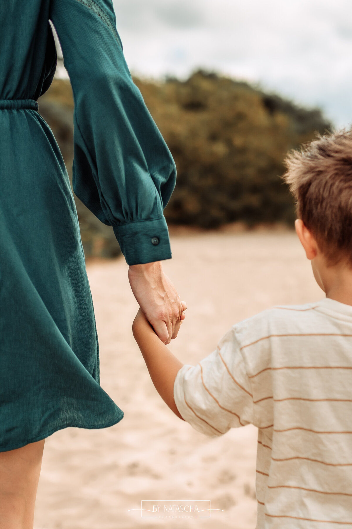 Mama en zoon lopen hand in hand over het zand van de duinen in de Bedafse Bergen in Uden