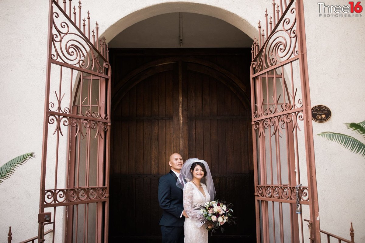 Bride and Groom pose together in the large gated archway