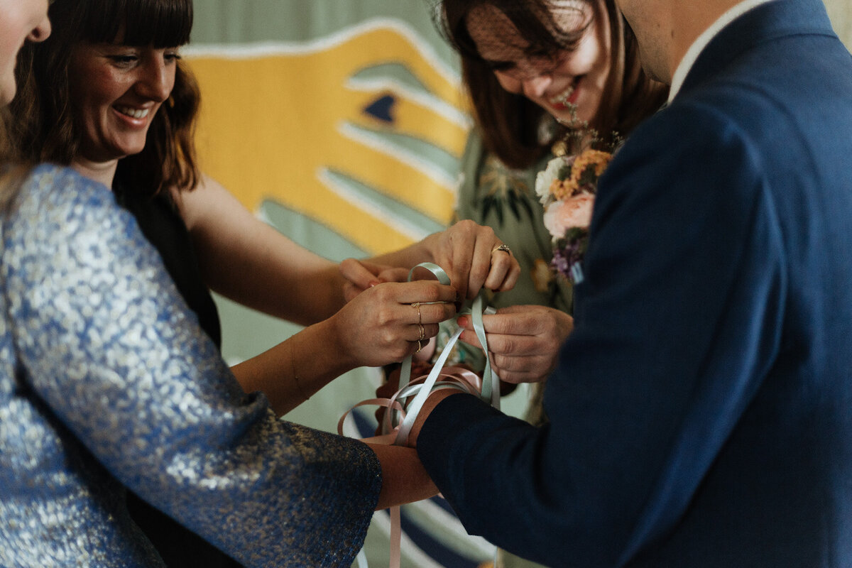tying ribbon around bride and groom wrists