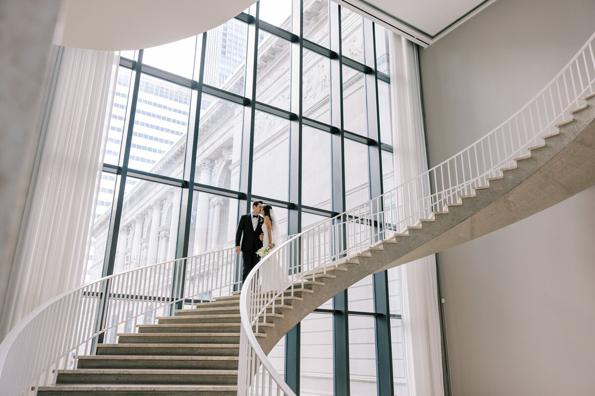 A wide, cinematic wedding portrait of a bride and groom inside the Art Institute of Chicago, showcasing grand architecture and timeless elegance.