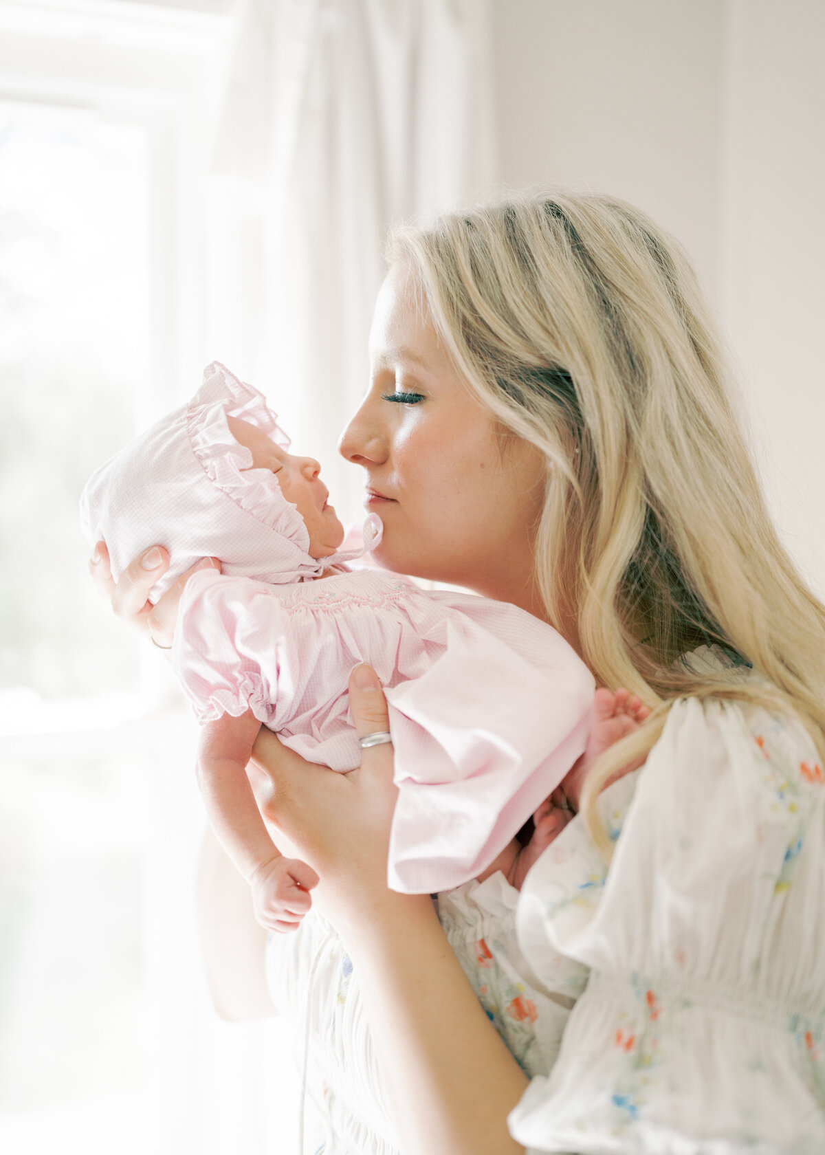 Woman holding sleeping newborn baby in a bonnet in virginia photographer session