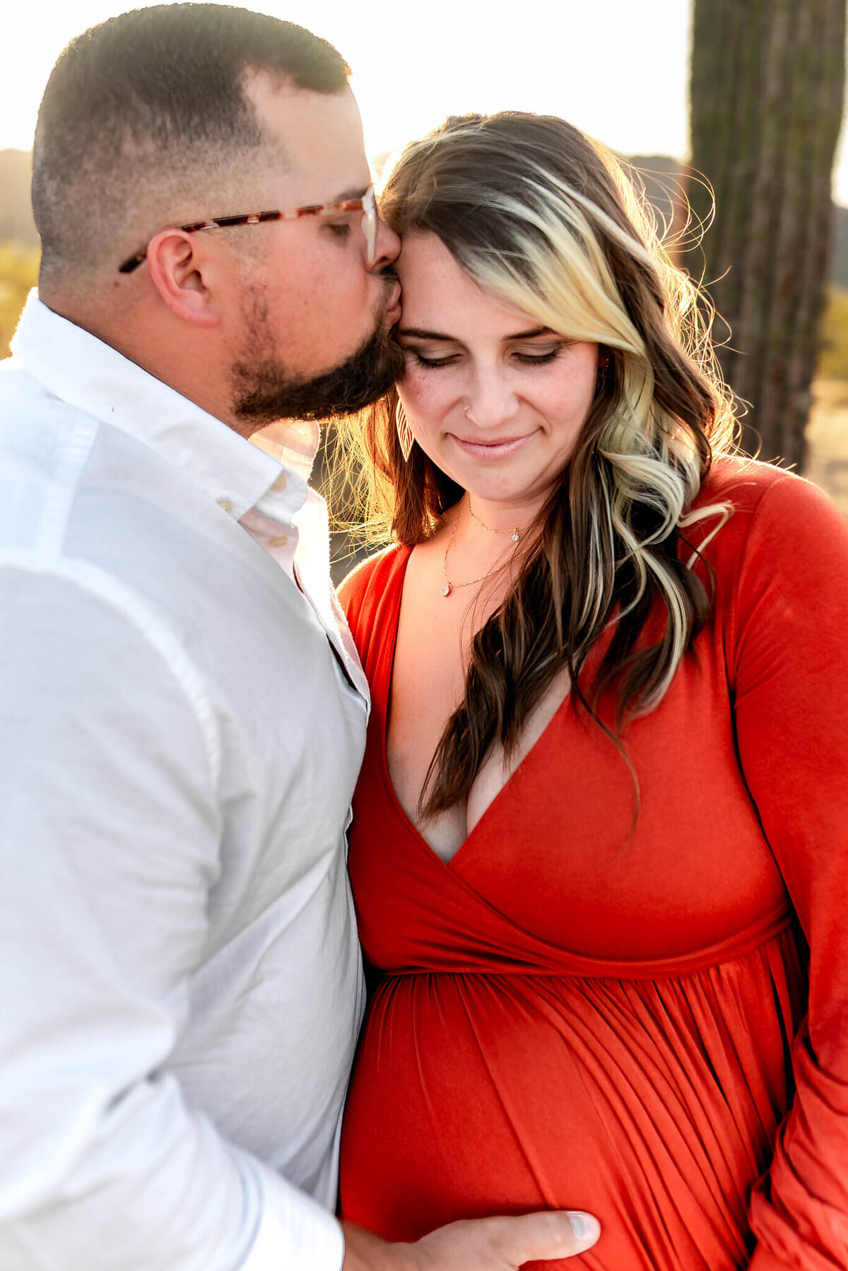 Sweet moment captured by Cactus & Pine Photography of husband gently kissing his expecting wife's temple