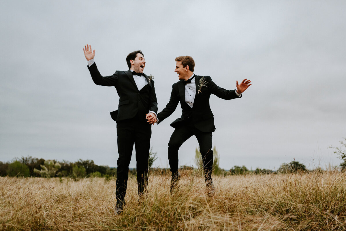 grooms jumping in air in field