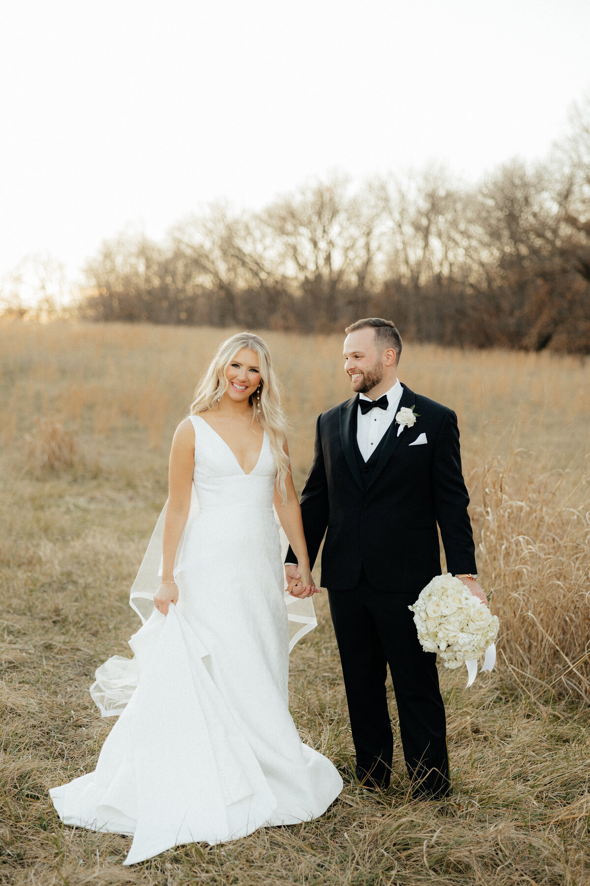 Sophie and Kyle standing in a field smiling at the camera.