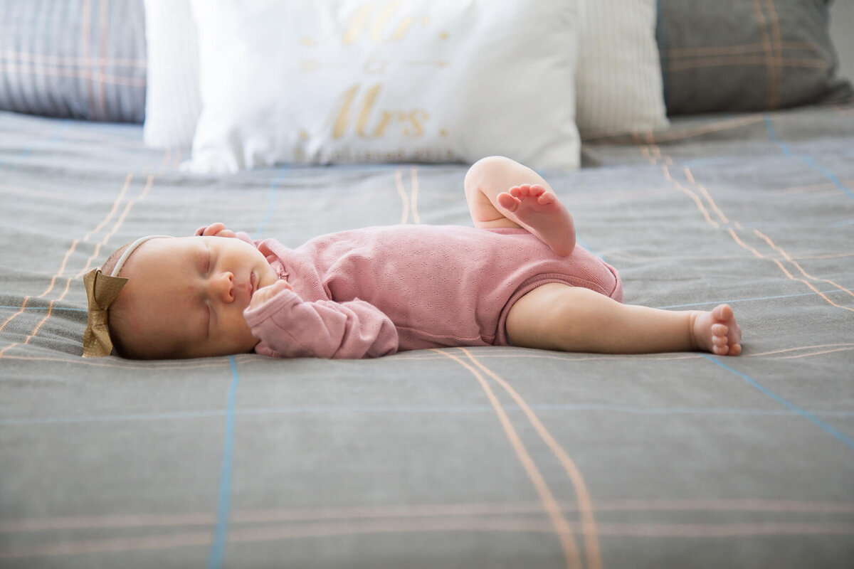 newborn baby girl laying on a gray bed