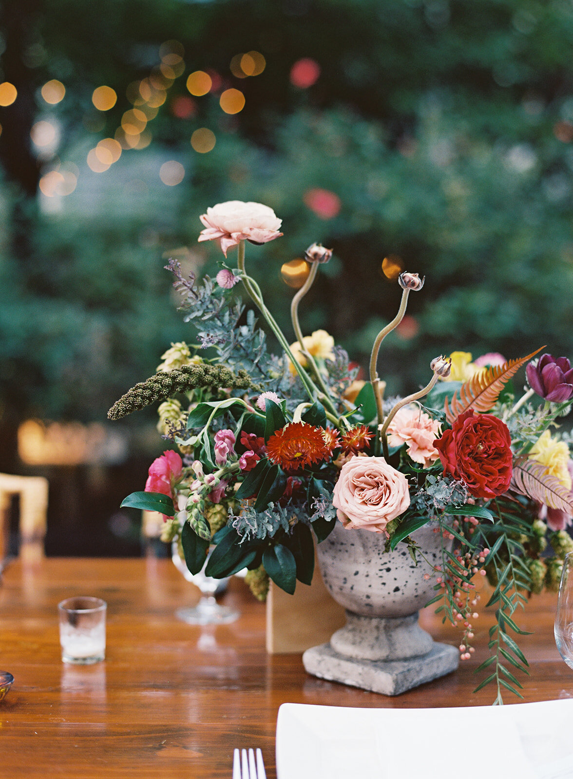 Welcome dinner on the front drive with wildflower centerpieces using ranunculus, chinos, hops, blackberries, persimmons, hops, garden roses, and natural, asymmetrical greenery. RT Lodge and Nashville wedding florist.