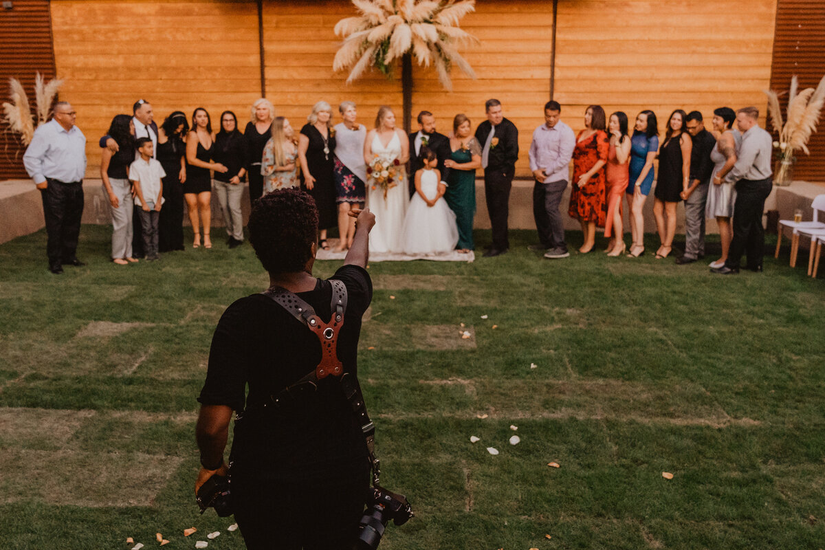 A wedding couple kissing while sitting at a table.