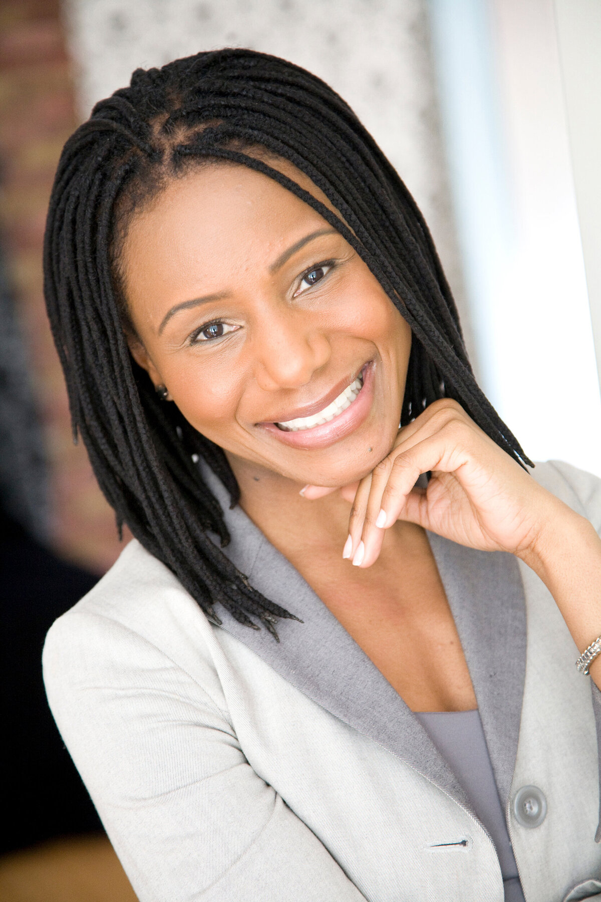 A black female with braids posing for a headshot with her hand under her chin