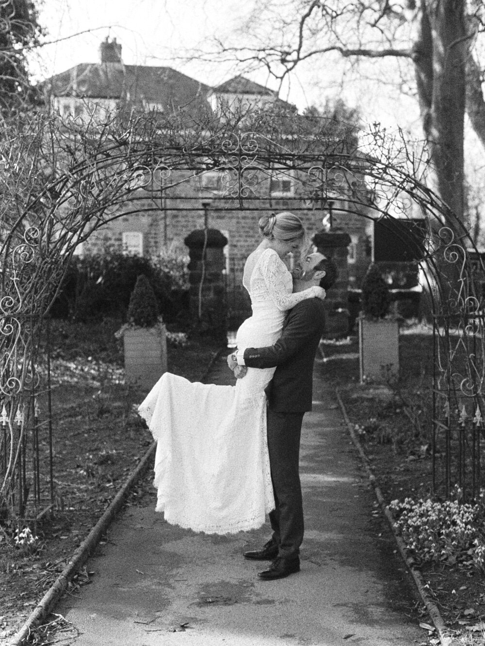 groom ligting bride outdoors captured on black and white film camera