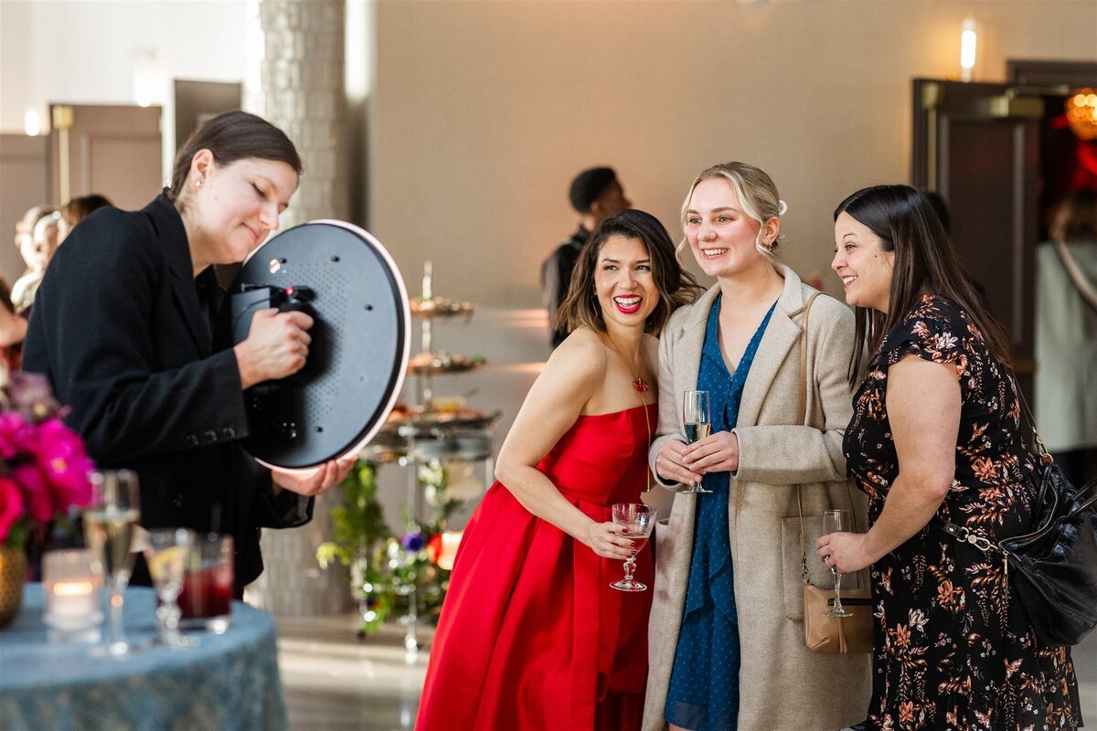 Large gathering at a Baroque-themed event, with guests dressed in formal attire mingling amid lavish decor including gilded furniture, crystal chandeliers, and rich drapery in a grand, ornately detailed space