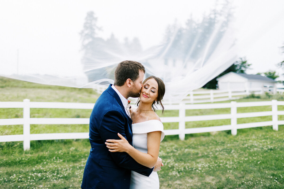 groom kissing his bride under the veil at Abella Farm