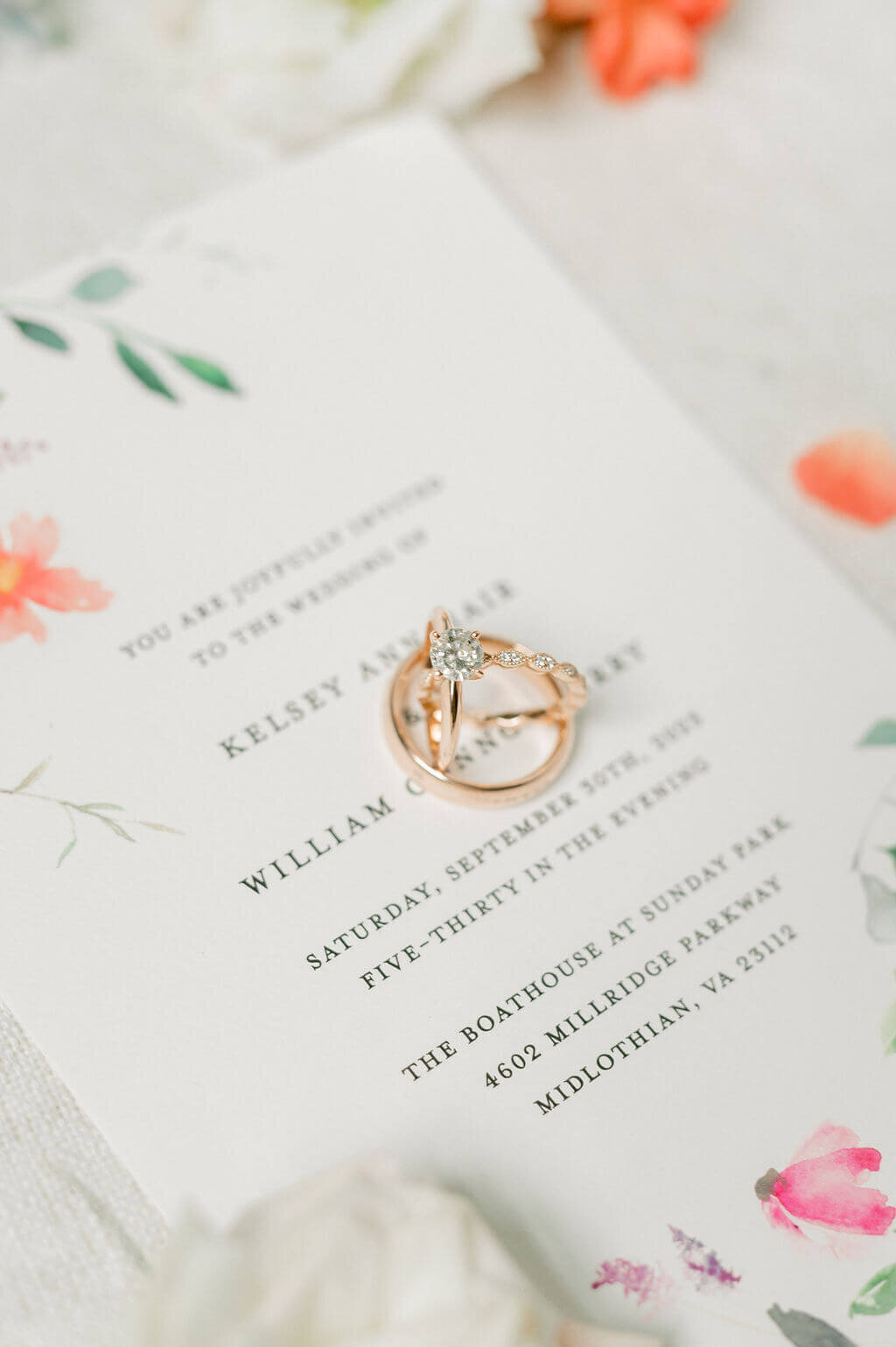 Close up image of wedding rings stacked within one another and sitting on a wedding invitation.