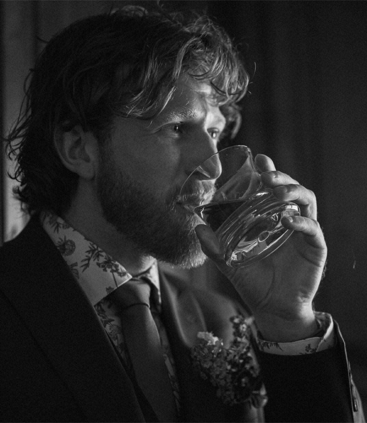 groom drinks a glass of whiskey while wearing his suit on his wedding day in Bend, OR
