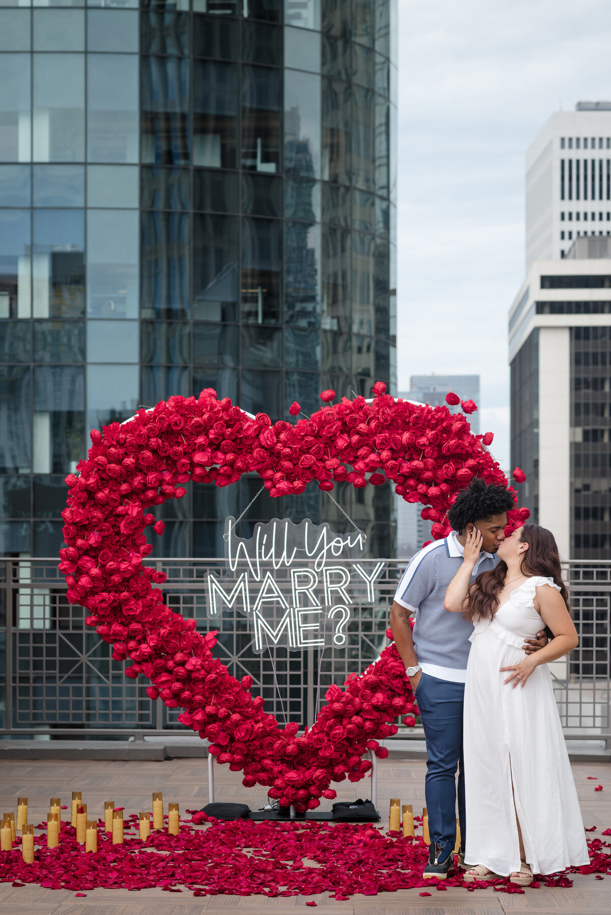 Romantic Uptown Charlotte proposal setup with red roses, candles, and skyline view, photographed by proposal photographer in Charlotte.