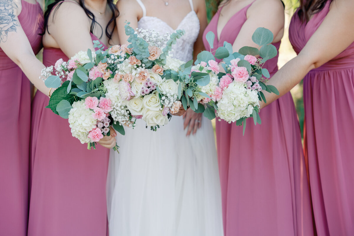 bride and bridesmaids standing together and holding their bouquets together for a detail shot of the florals captured by wedding photographer bay area