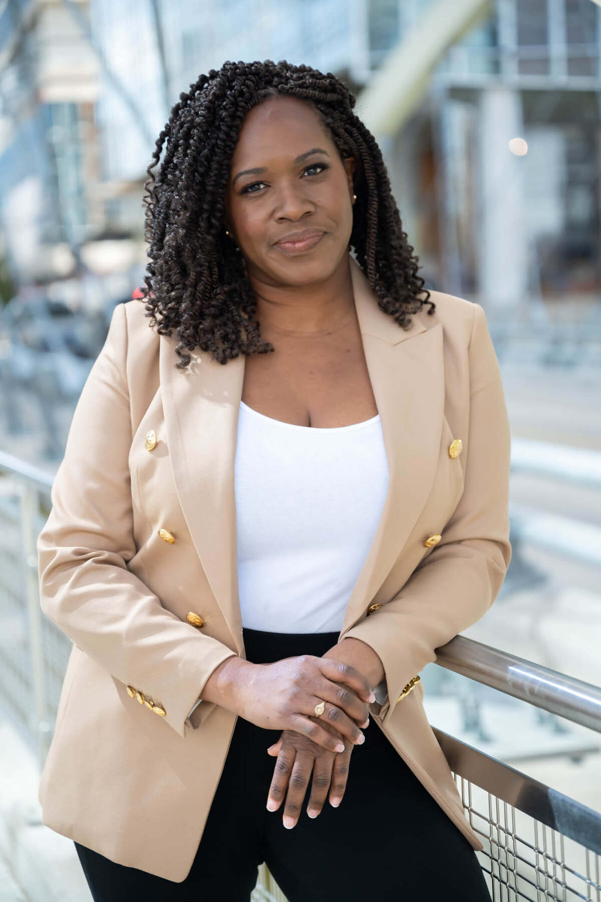 An image of a black woman with short curly hair, standing outdoor smiling to the camera