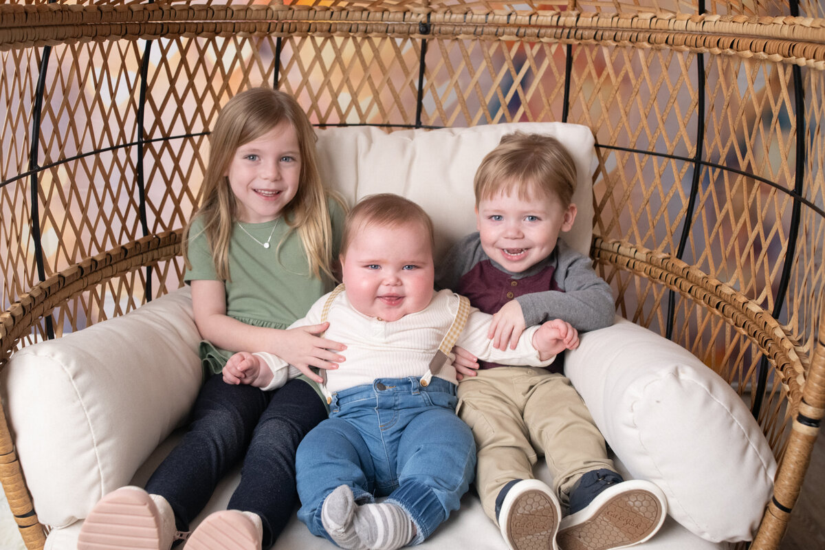 happy children sitting together in a wicker chair