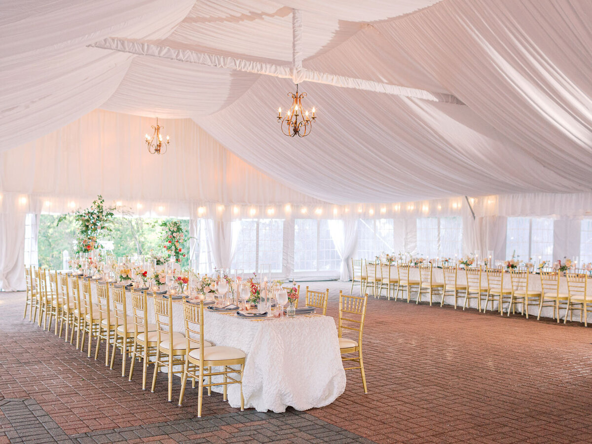 Luxury wedding venue with chandeliers, long table, and golden chairs