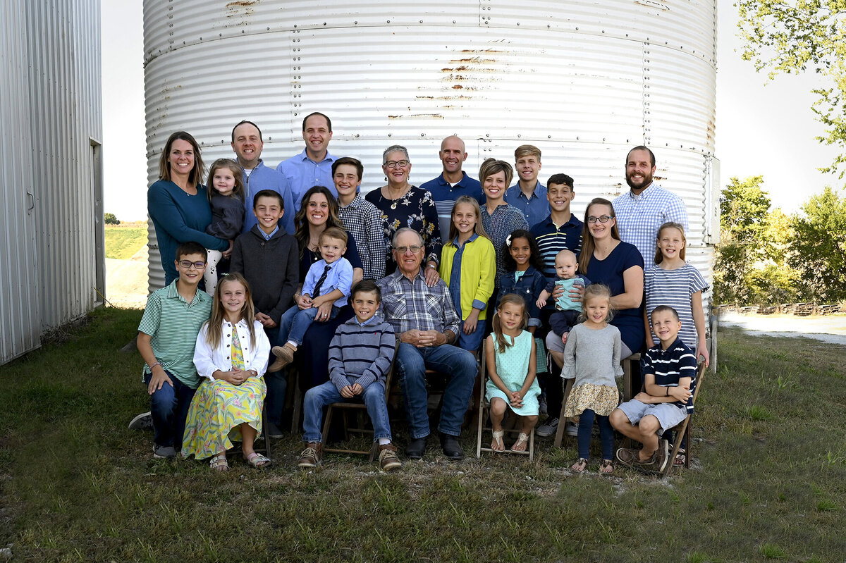 Many family members sit in front of a silo for their family photos