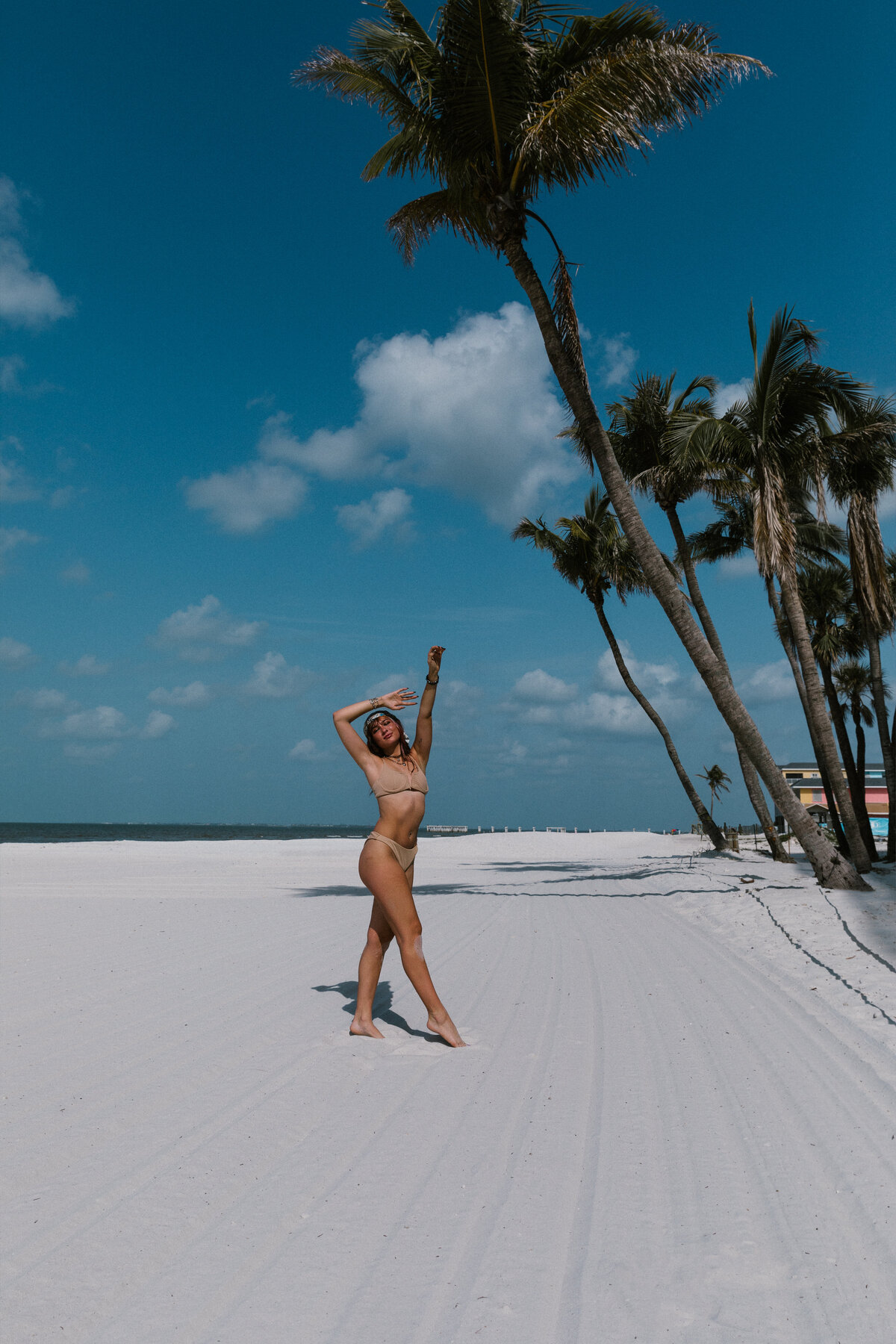 woman standing under a palm tree on fort myers beach in florida