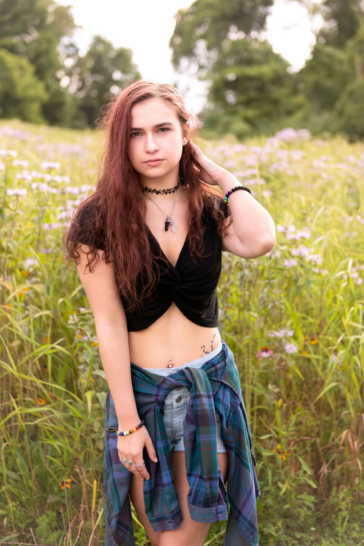 High school senior girl standing in field of tall grasses