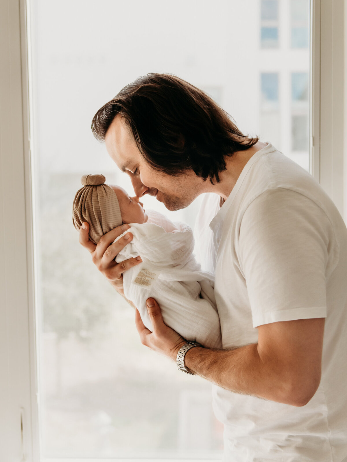 Newborn Photography, Dad kissing baby girl on the nose by the window.