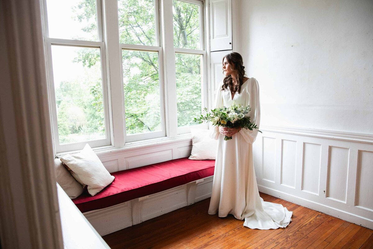 bride with bouquet looking out window Duke Sculpture Garden at Dixon Mansion