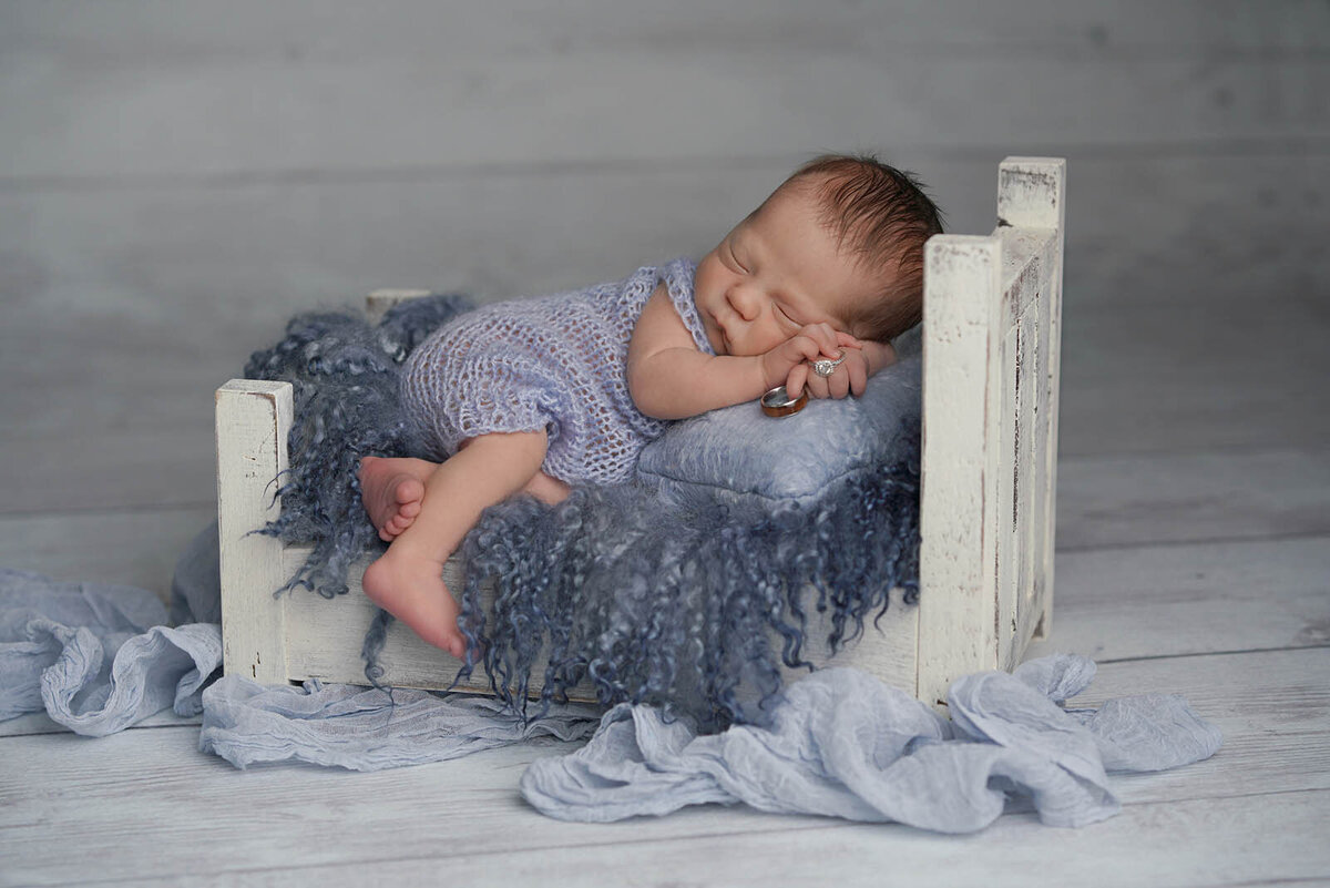 Newborn sleeping on a blue mini-bed