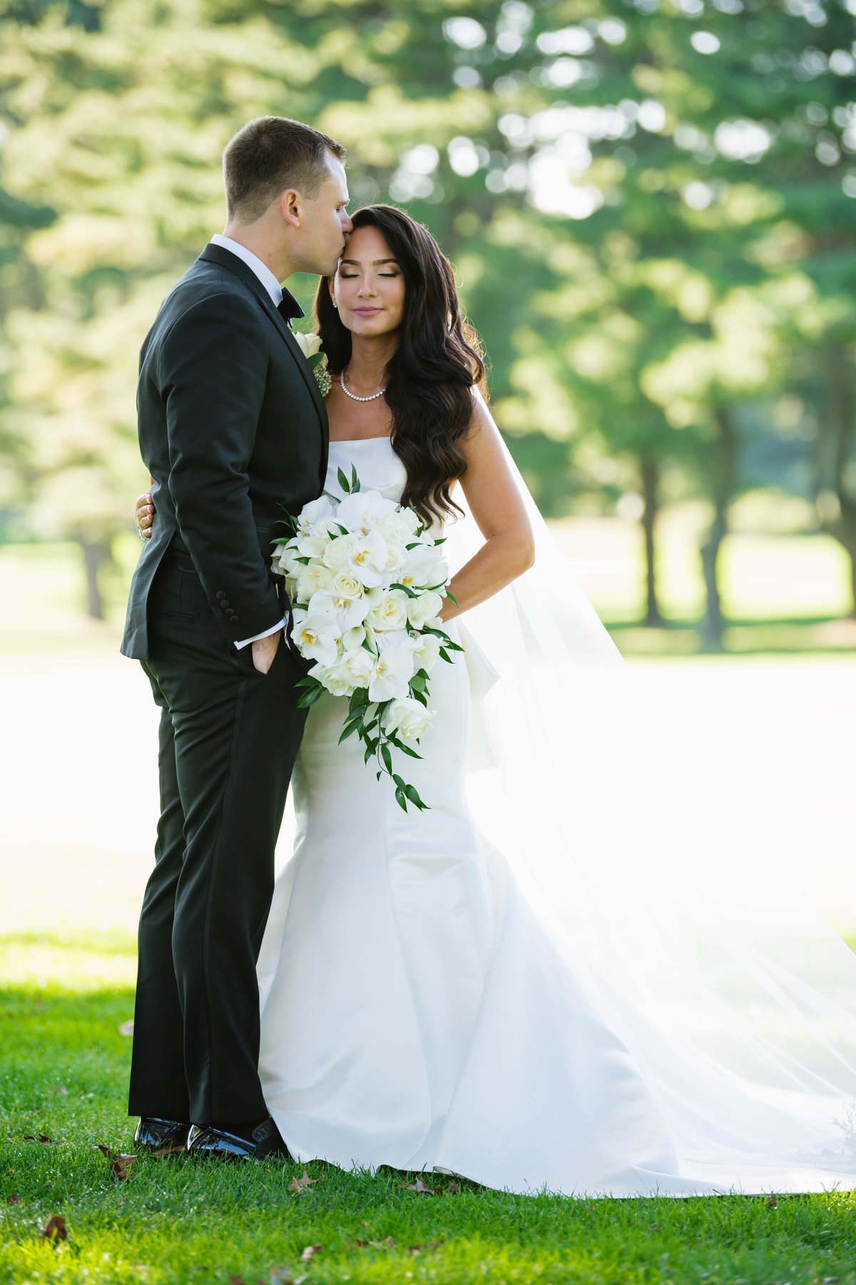 groom kissing his bride on the forehead outside wedding at The Muttontown Club