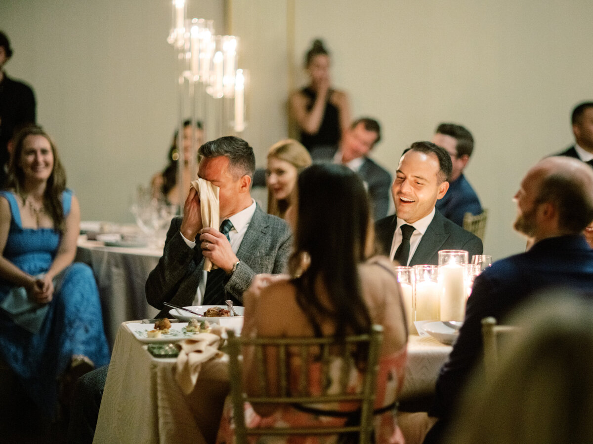 An amusing scene captured as a man laughs while hiding his face, showcasing humor, camaraderie, and the lightheartedness often present in joyous gatherings and celebrations.